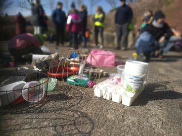 Flaschen, Drahtkörbe, Eierpackungen, Plastikeimer: der Müll wartet darauf, dass aus ihm etwas gebaut wird. Der Müll ausgebreitet, dahinter ein paar Blumenthaler:innen versammelt. 