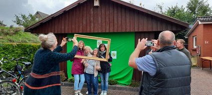5 Frauen halten einen Bilderrahmen und werden damit fotografiert