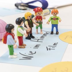 Kokreation - Wie im Himmel Playmobilfiguren stehen auf einer Moderationskarte