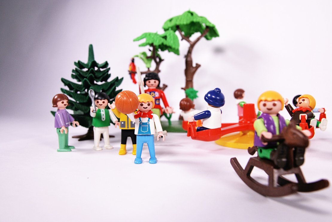 Kulturpaket Kultur in Kitas Kinder spielen auf einem Spielplatz: Schaukeln auf einem Pferd, spielen Ball.