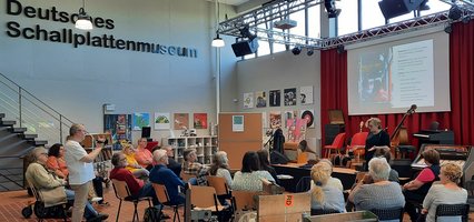 Menschen sitzen im Nortorfer Schallplattenmuseum vor einer Bühne