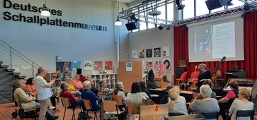 Infoabend Kulturhaltestellen Menschen sitzen im Nortorfer Schallplattenmuseum vor einer Bühne